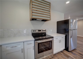 New kitchen offers quartz countertops with beautiful backsplash and white cabinetry.